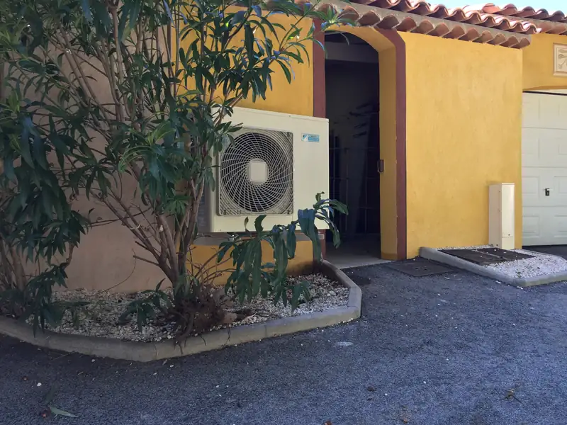 Groupe extérieur multisplit Daikin posé contre la façade d'une maison, à côté de l'entrée du garage